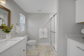 A modern bathroom with a white sink, toilet, and shower area.