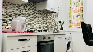 A compact kitchen with a gas stove, oven, and a washing machine. - SAN GIOVANNI APARTMENT 80 SQM (Roma)