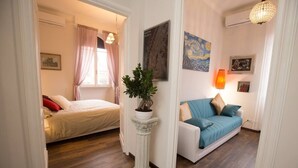 A room with a bed, a sofa, a potted plant, and a painting on the wall. - SAN GIOVANNI APARTMENT 80 SQM (Roma)
