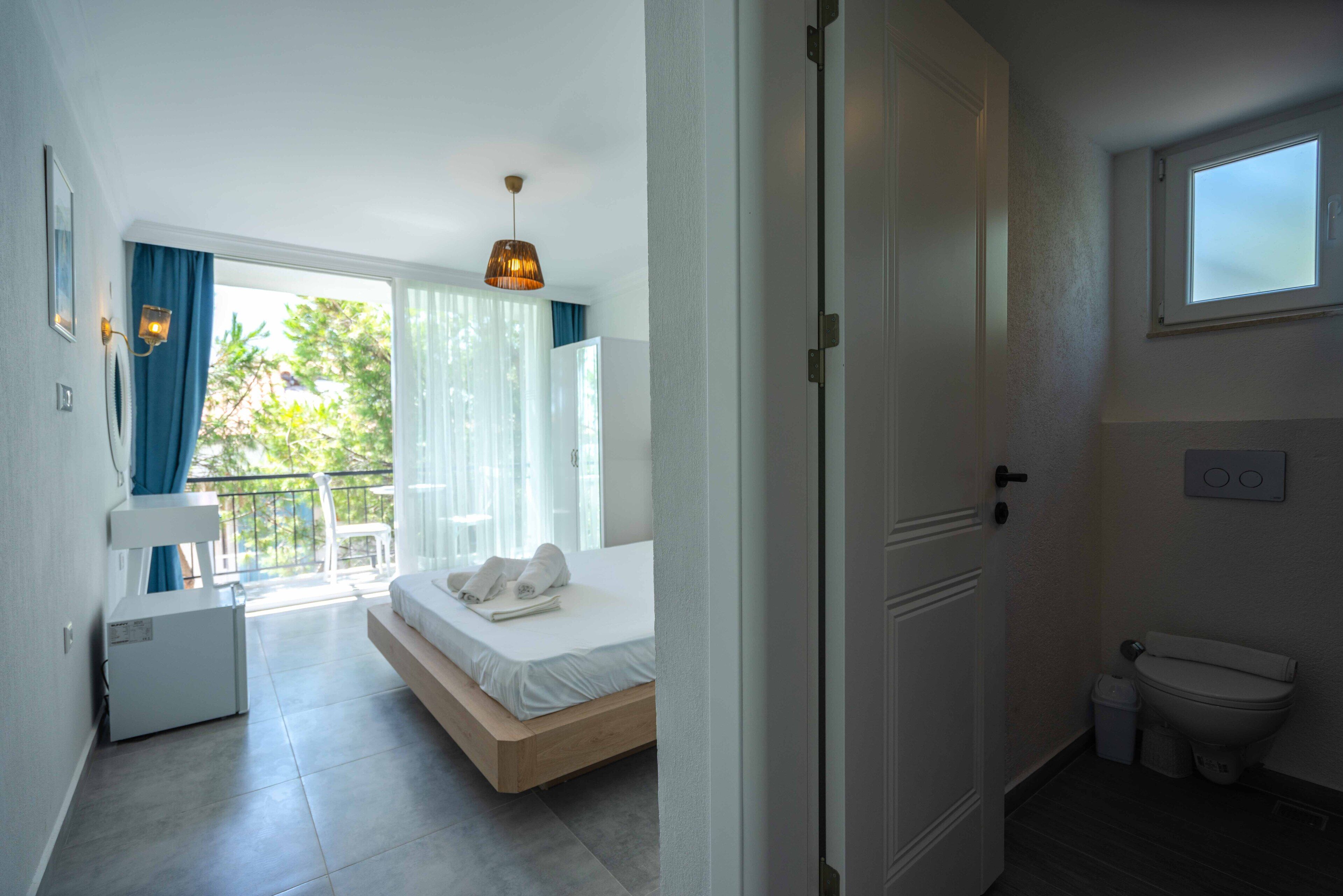 Un dormitorio con cama, un escritorio pequeño, una ventana y un balcón.