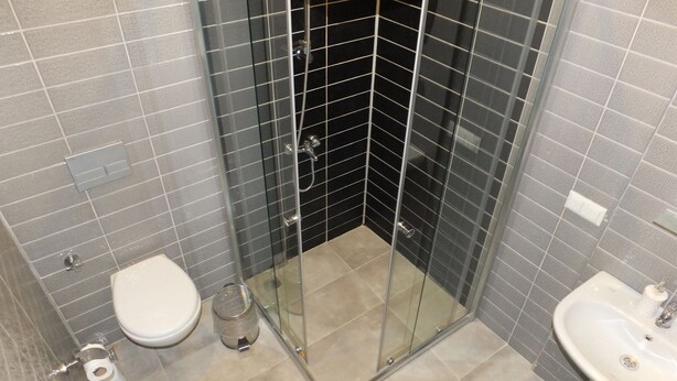 A bathroom with a toilet, a glass-enclosed shower, and a sink. - Sole'n Blu Hotel (Kas)