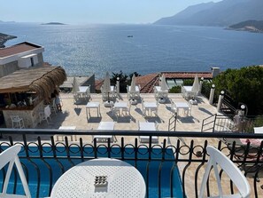 A poolside area with lounge chairs and tables, overlooking a body of water and distant land. - Sole'n Blu Hotel (Kas)