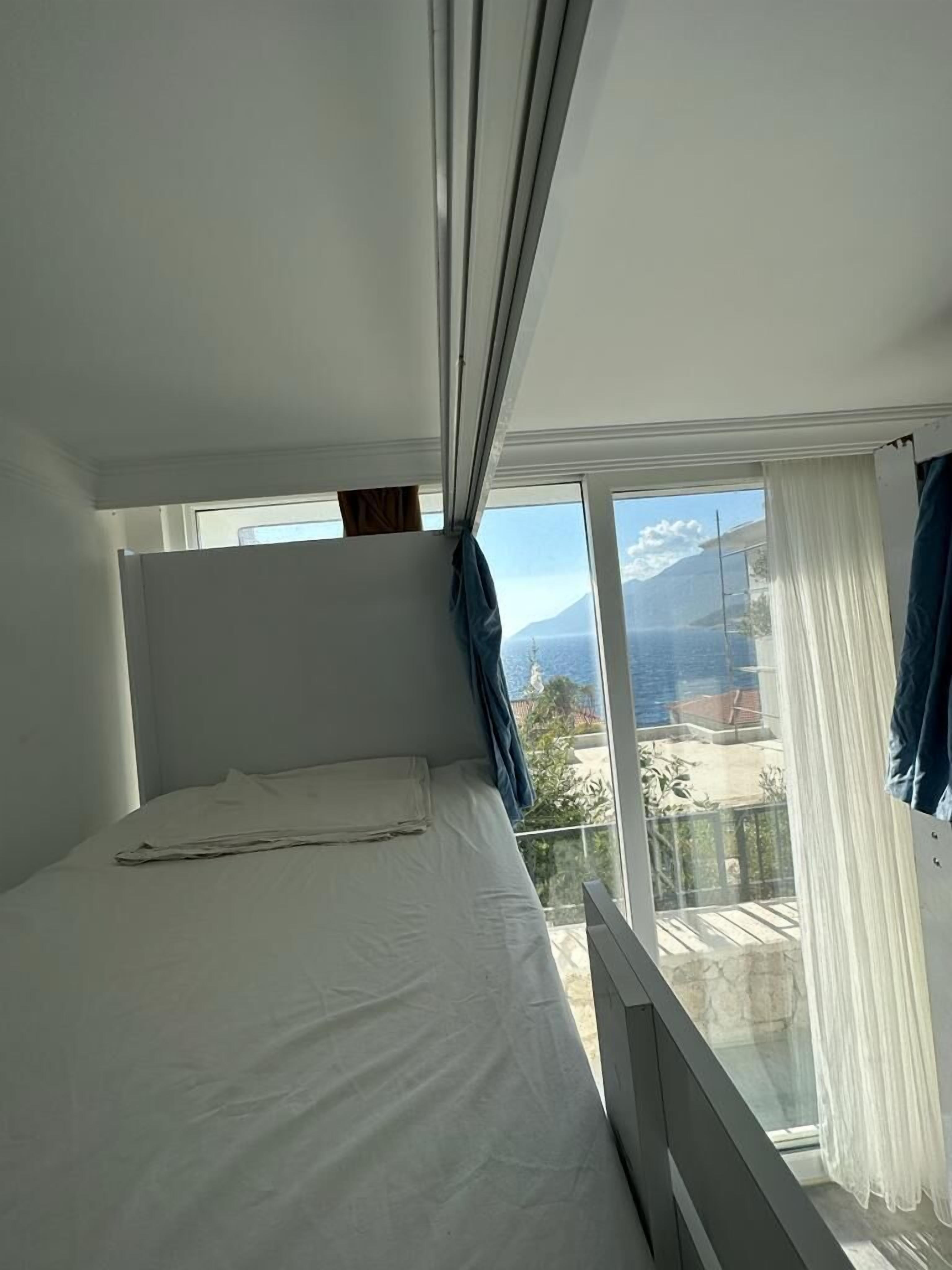 Un dormitorio con cama, ventana con cortinas y vistas a un paisaje montañoso.