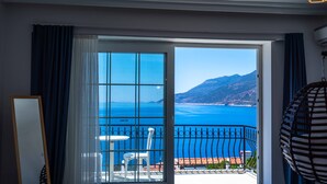 A room with a large sliding glass door leading to a balcony with a view of the sea and mountains. - Sole'n Blu Hotel (Kas)