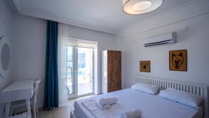 A hotel room with a bed, a desk, a chair, a wardrobe, and a view of the sea. - Sole'n Blu Hotel (Kas)