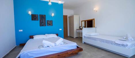 A hotel room with a large bed, a smaller bed, a wardrobe, a mirror, and artwork on the wall.
