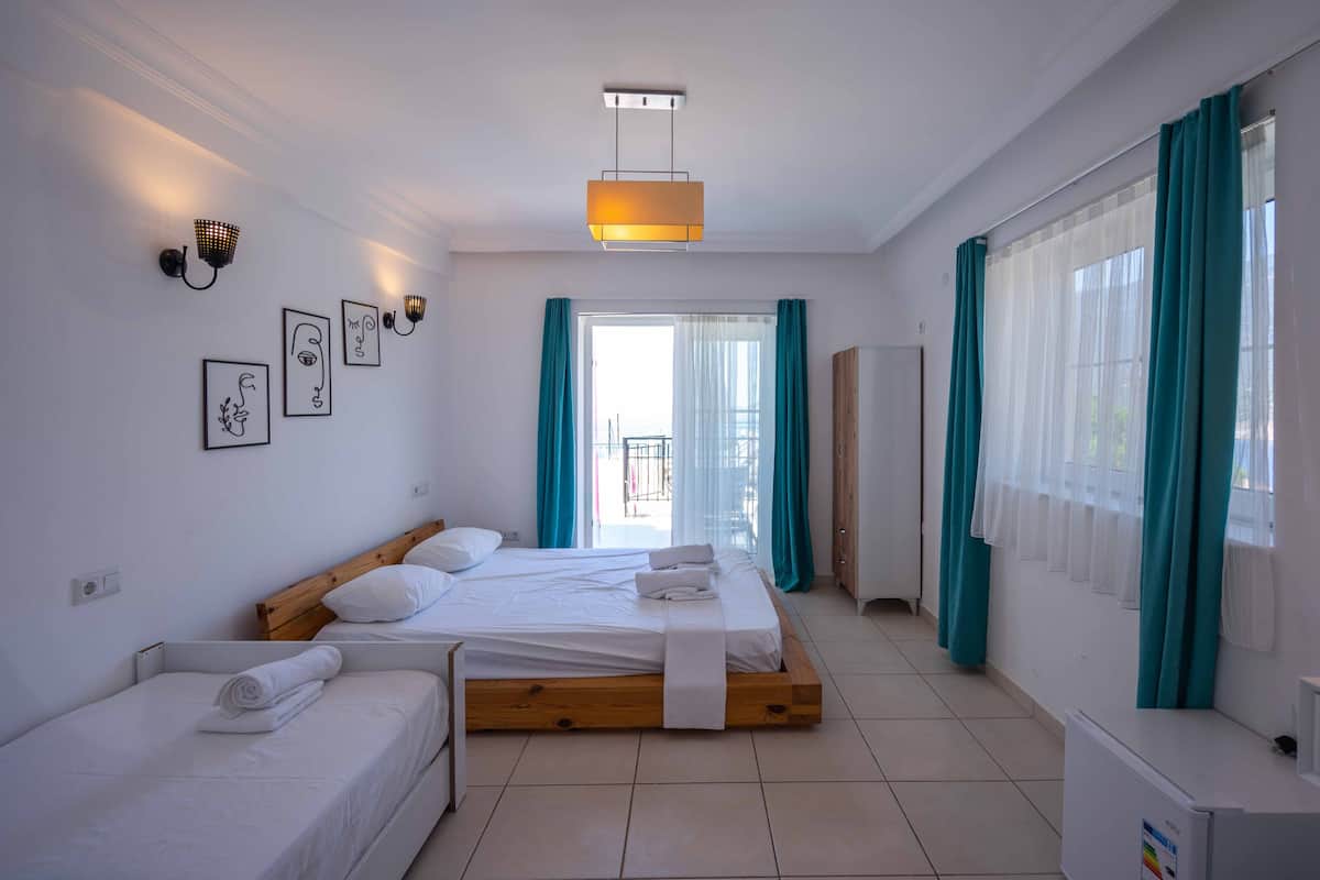 A modern bedroom with two beds, a wooden headboard, and a large window with teal curtains.