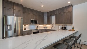 Una cocina moderna con una isla grande, electrodomésticos de acero inoxidable y alacenas de madera oscura.