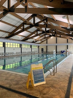 Une piscine intérieure dotée de couloirs clairement délimités, d’un poste de surveillance pour les sauveteurs et d’un panneau indiquant les couloirs réservés aux exercices aquatiques et à la nage en longueur.