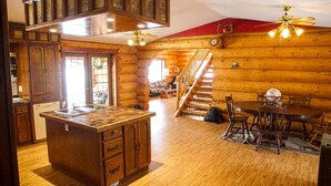 L’intérieur d’une cabane en rondins comprend une cuisine, un coin repas et un escalier menant à une mezzanine.