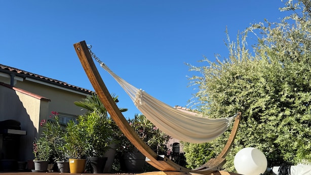 A hammock tied between wooden posts, a swimming pool, and potted plants.