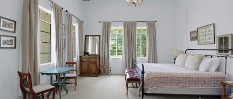 Une chambre à coucher avec un lit, une commode en bois, un bureau et des chaises.