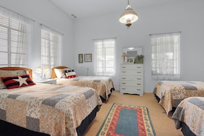 Une chambre avec deux lits, une commode et un miroir.
