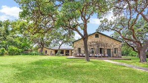 A rustic stone building with a covered patio and outdoor seating area. - Live Oak Ranch - Swimming Pool Property with Sleeping for 20! (Spring Branch)