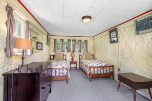 Un dormitorio con dos camas de madera, un aparador, una mesita de noche y un escritorio.