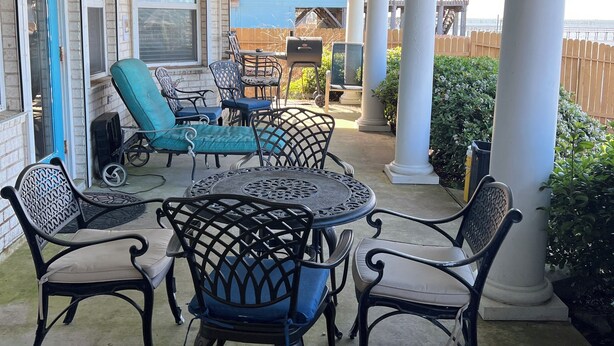 Un patio couvert, aménagé avec du mobilier d’extérieur, notamment une table et des chaises, et doté d’un ventilateur de plafond.