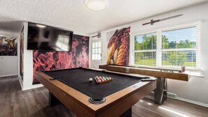 A pool table with a billiard cue and balls, a mounted television, and a window with blinds. - ★Dragon’s Lair★Private Home w/ Arcade & Minigolf★ (Westerville)