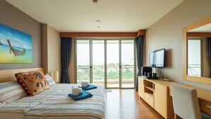 A hotel room with a large bed, a desk with a TV, and a balcony with a view. - 503c - 1 Bdr Condo With Seaview Boathouse Hua Hin (Cha-am)