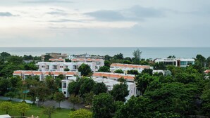 A residential area with multiple white buildings with orange roofs, surrounded by greenery and a view of the sea. - 503c - 1 Bdr Condo With Seaview Boathouse Hua Hin (Cha-am)