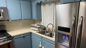 A kitchen with blue cabinets, stainless steel appliances, a double sink, and a wooden table. - Prime spot located on the water, Luxury living Bayou front living at its finest. (Chauvin)