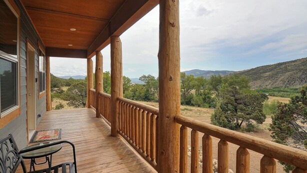 Une terrasse en bois avec une balustrade donnant sur un paysage montagneux.