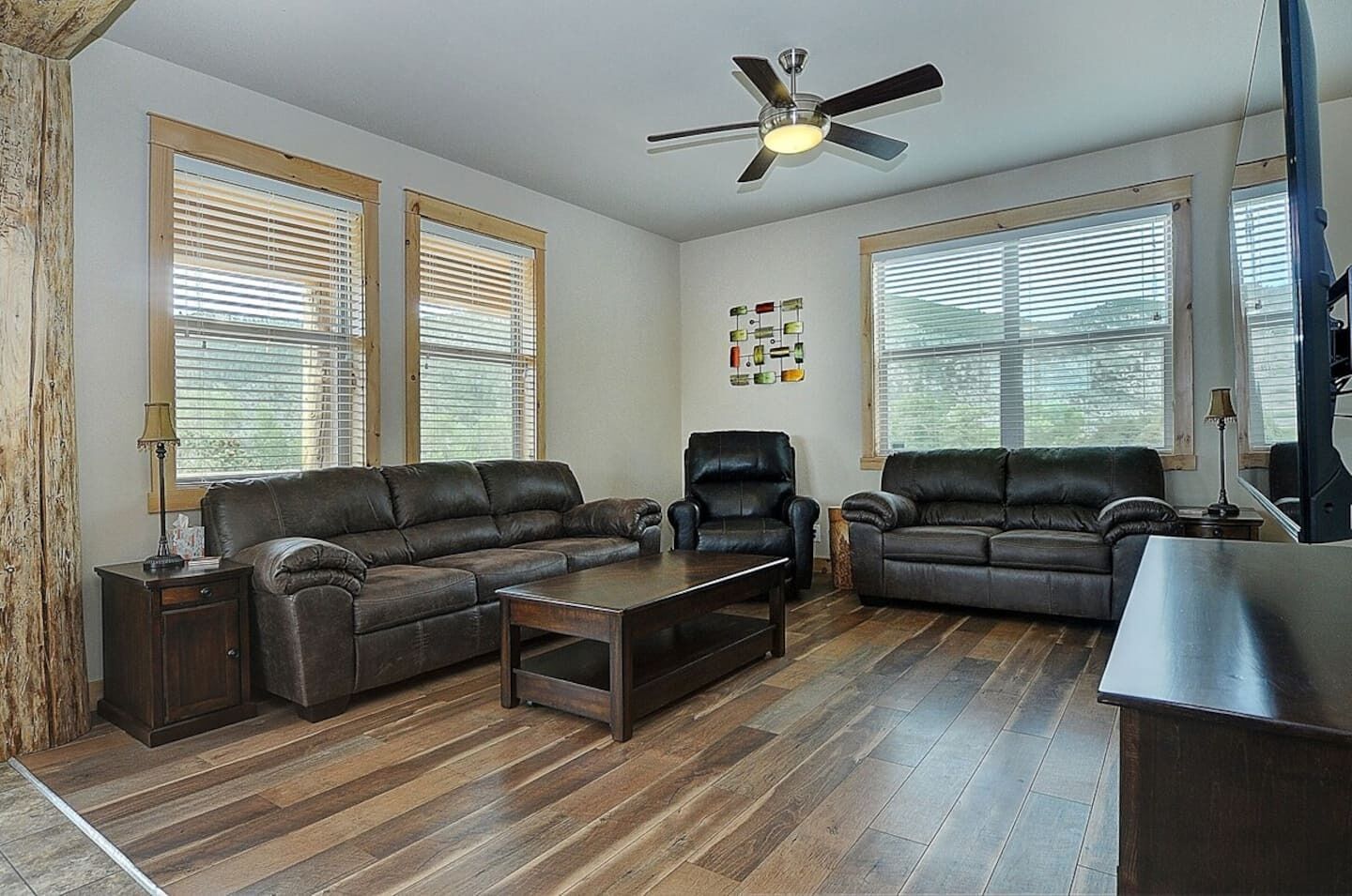 A living room with two leather sofas, a coffee table, a chair, and a ceiling fan.