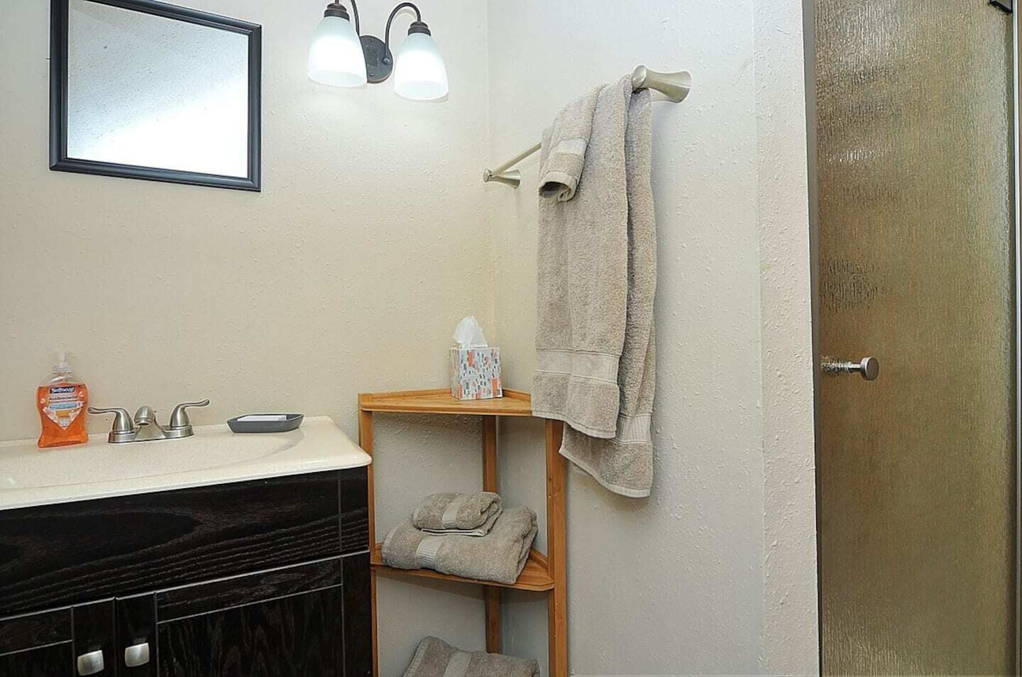 Une salle de bain équipée d’un lavabo, d’un miroir, d’un porte-serviettes et d’une porte.