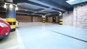 A parking garage with a skylight, brick walls, and bollards. - Daeyeon Welkin Hotel (Busan)