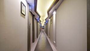 A long, narrow hotel corridor with doors on both sides, a central walkway, and a ceiling with recessed lighting. - Daeyeon Welkin Hotel (Busan)