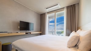 Habitació d'hotel moderna amb un llit gran, una televisió de pantalla plana penjada a la pared i un balcó amb vista al cel.