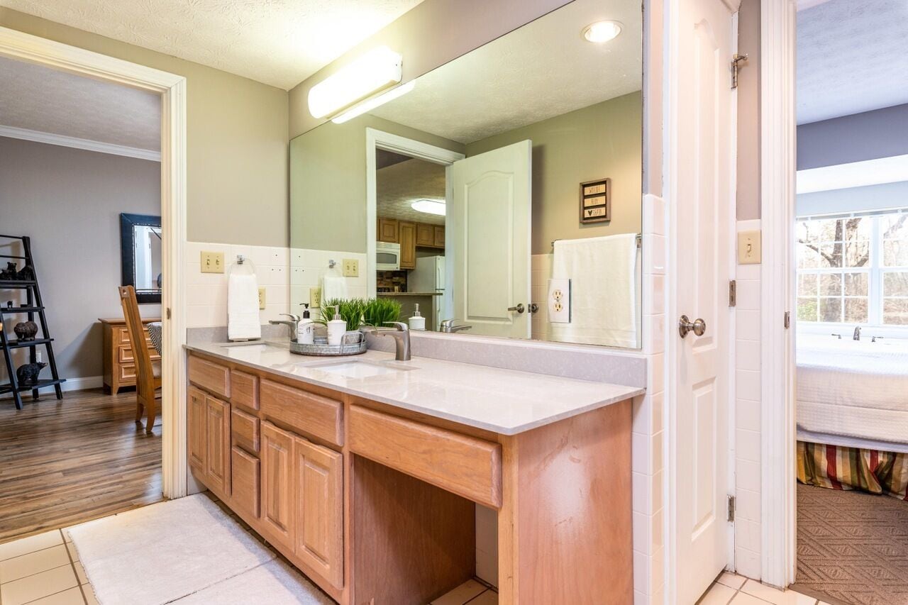 A modern kitchen with a large island, wooden cabinets, and a large mirror.