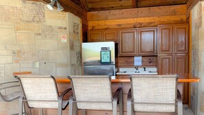 A rustic kitchen with a stone wall, wooden cabinets, and a stainless steel refrigerator. - Golf View Condo - Next to Dollywood (Pigeon Forge)