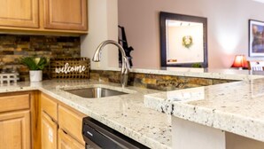 A kitchen with granite countertops, wooden cabinets, a stainless steel sink, and a welcome sign. - Golf View Condo - Next to Dollywood (Pigeon Forge)