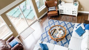 A spacious living room with a large sofa, a brown leather chair, and a white entertainment unit. - Spring Lily Retreat - Spacious, Lakefront, Hot Tub, Private Dock, Peaceful Cove! (Speedwell)