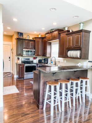 A modern kitchen with dark wood cabinets, stainless steel appliances, and a central island with bar stools.