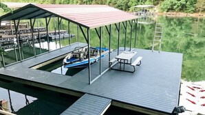 A dock with a covered seating area, a boat, and a picnic table. - Spring Lily Retreat - Spacious, Lakefront, Hot Tub, Private Dock, Peaceful Cove! (Speedwell)