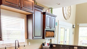 A kitchen with dark wooden cabinets, a granite countertop, a built-in dishwasher, and a patterned rug. - Spring Lily Retreat - Spacious, Lakefront, Hot Tub, Private Dock, Peaceful Cove! (Speedwell)