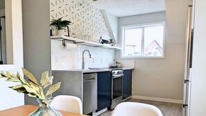 Eine moderne Küche mit weißen Schränken, einem eingebauten Backofen und einem Fenster über der Spüle.