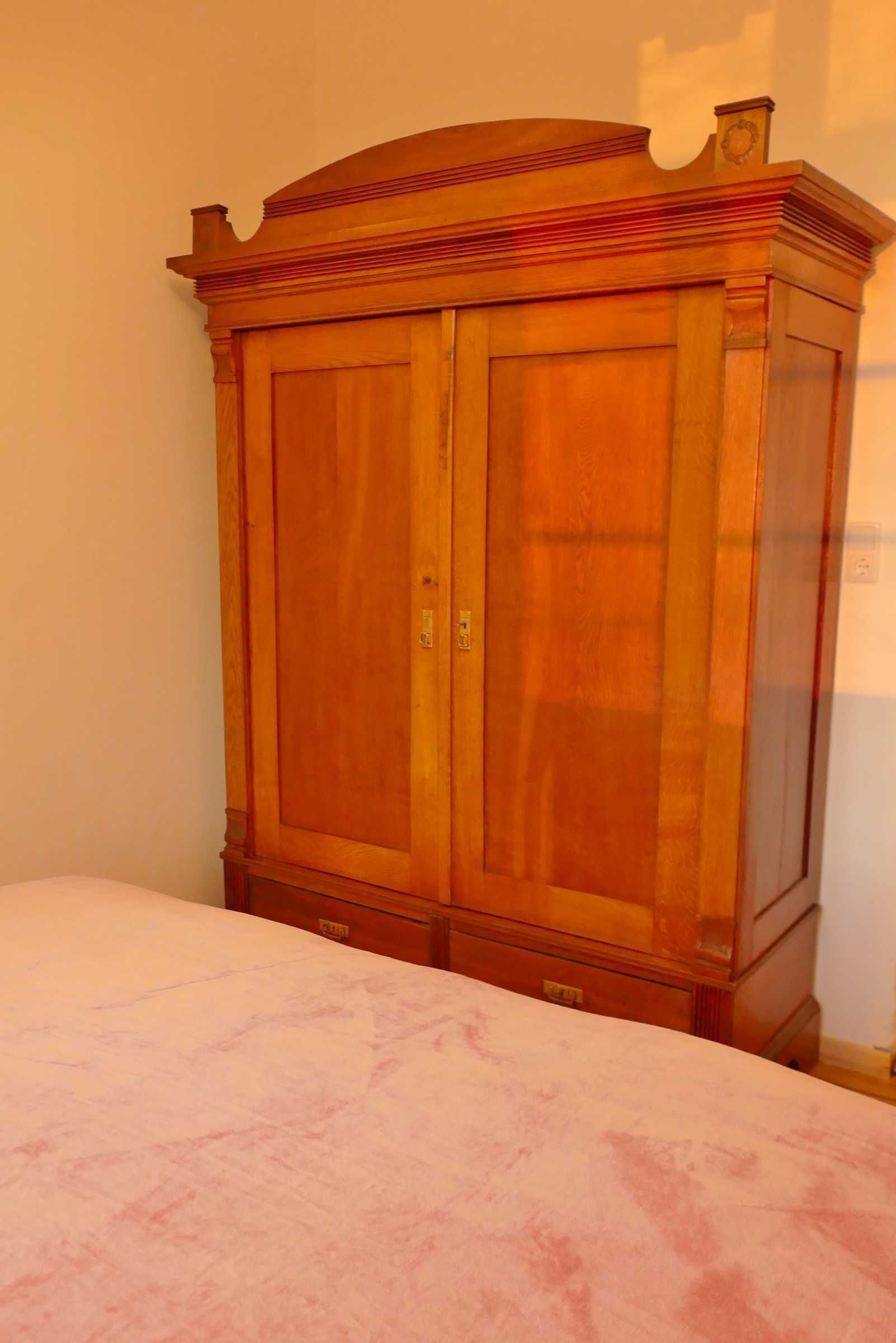 A wooden wardrobe with two doors and a small shelf on top.