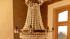 A dining area with a chandelier, a table set for two, and a window with a view of the outdoors.