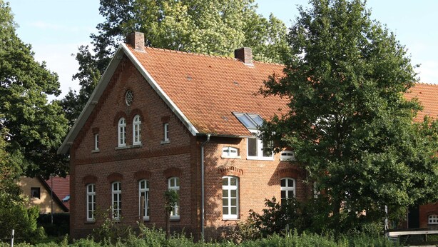 A brick building with a sloped roof and multiple windows.