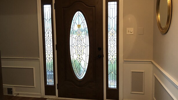 A wooden front door with a glass panel and a decorative glass window.