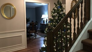 A staircase with a wooden handrail and a Christmas tree decorated with lights and ornaments.