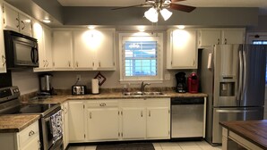 A modern kitchen with white cabinets, stainless steel appliances, a granite countertop, and a window with a view.