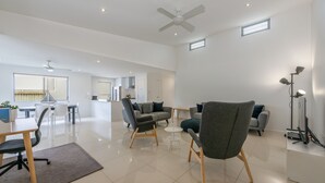 Een ruime woonkamer met een modern design, met een bank, stoelen, een salontafel en een tv-meubel.