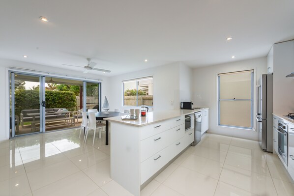 A modern kitchen with a large island, sliding glass doors leading to an outdoor area, and a view of the outdoors.