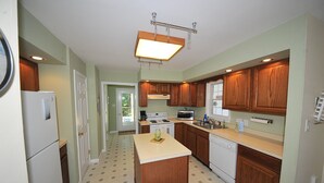 A compact kitchen with wooden cabinets, a central island, and a built-in dishwasher.