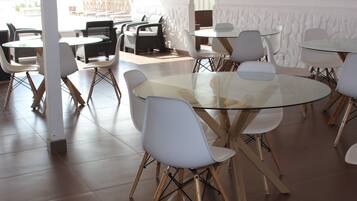 Un espace repas moderne avec des tables rondes en verre et des chaises blanches, caractérisé par un design épuré et contemporain.