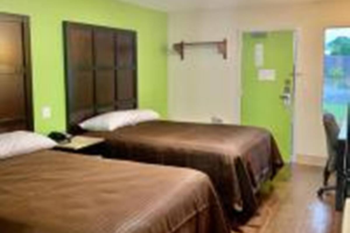 A hotel room with two single beds, a desk, and a chair.
