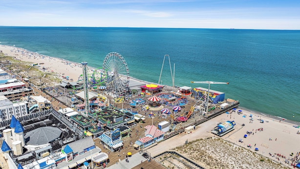 A coastal amusement park with a Ferris wheel, rides, and beach access.